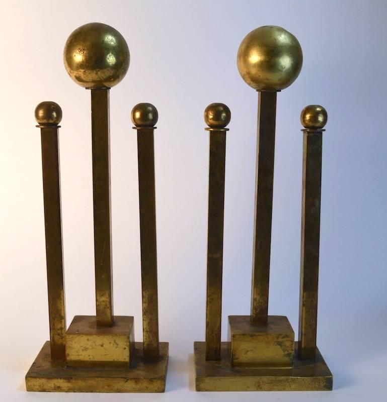 Pair of Art Deco brass andirons with squared vertical supports topped with brass balls. The finish shows wear, as shown.