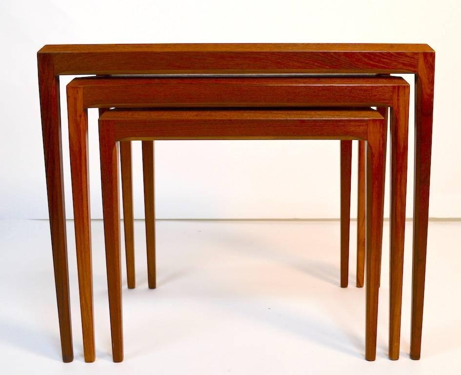 Sleek Danish modern nest of three teak tables by Johannes Andersen for CFC Mobler Silkeborg. Dimensions in listing are for the largest table.
 