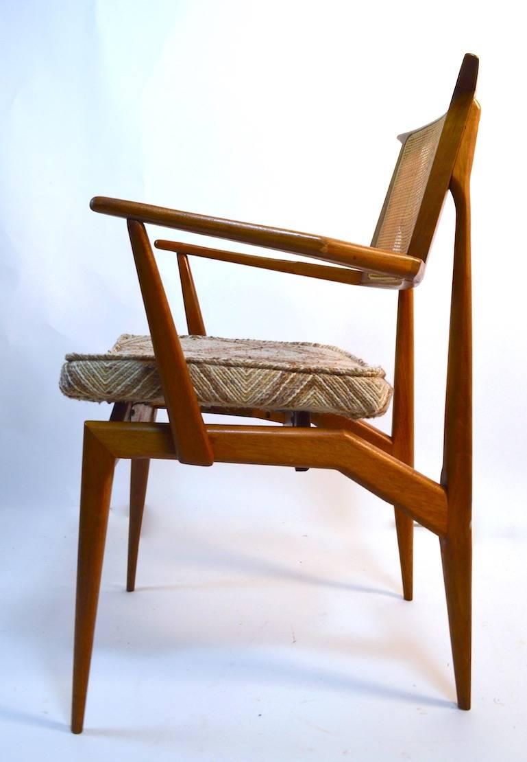 Set of six bench made Mid-Century Modern architectural dining chairs, two arm chairs, four armless. Caned back rests, solid wood frames, with upholstered seats. The upholstered seats show wear and re-upholstery is suggested.
Measures: Arm height