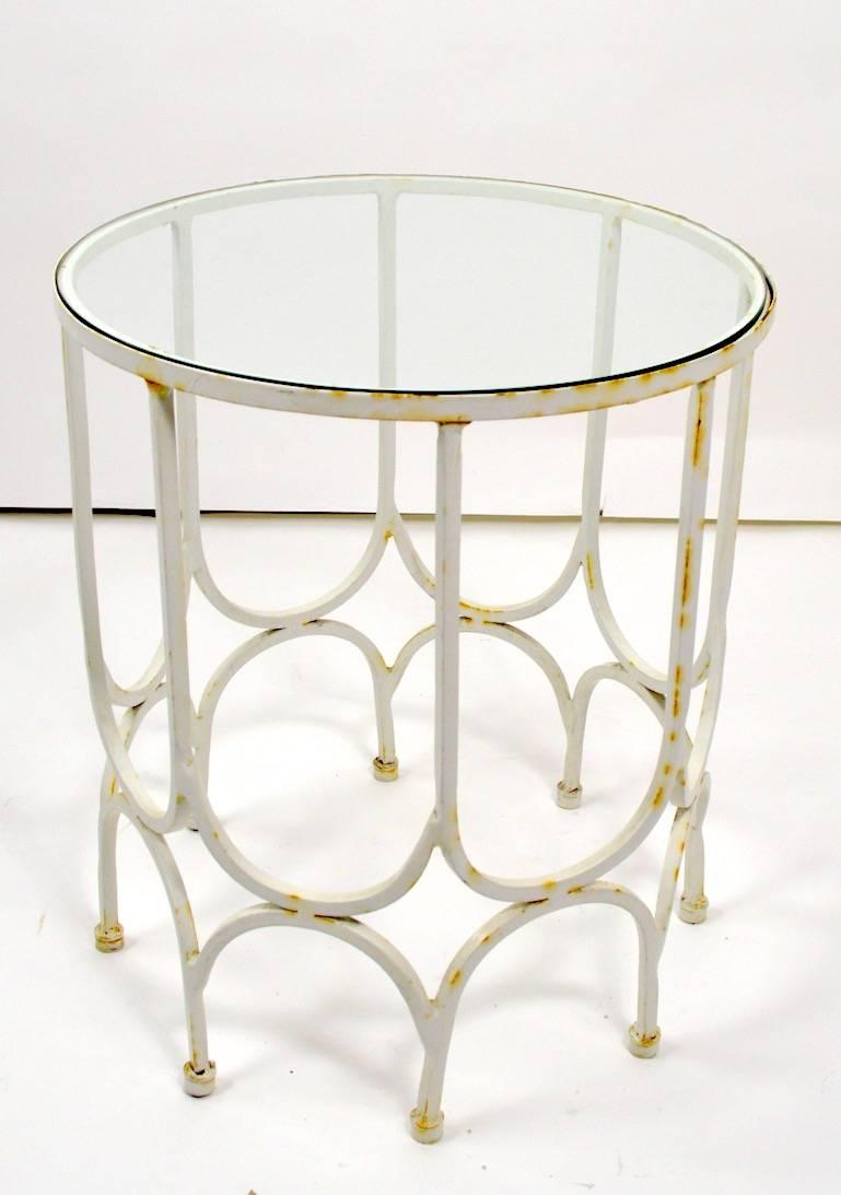 Pair of circular wrought iron, glass top tables.  Original finish shows some cosmetic wear, normal and consistent with age. Usable as is or we also offer custom powder coating if you want a more polished finish. Selling and priced as a pair.