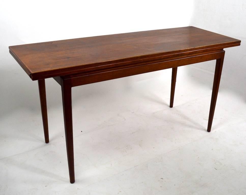 Gorgeous flip top console dining table designed by Jens Risom. This example is in clean, original condition.
Mid-Century Modern rationalist design, simple, sophisticated and elegant.
Measures: Width when open 42 inches.
    