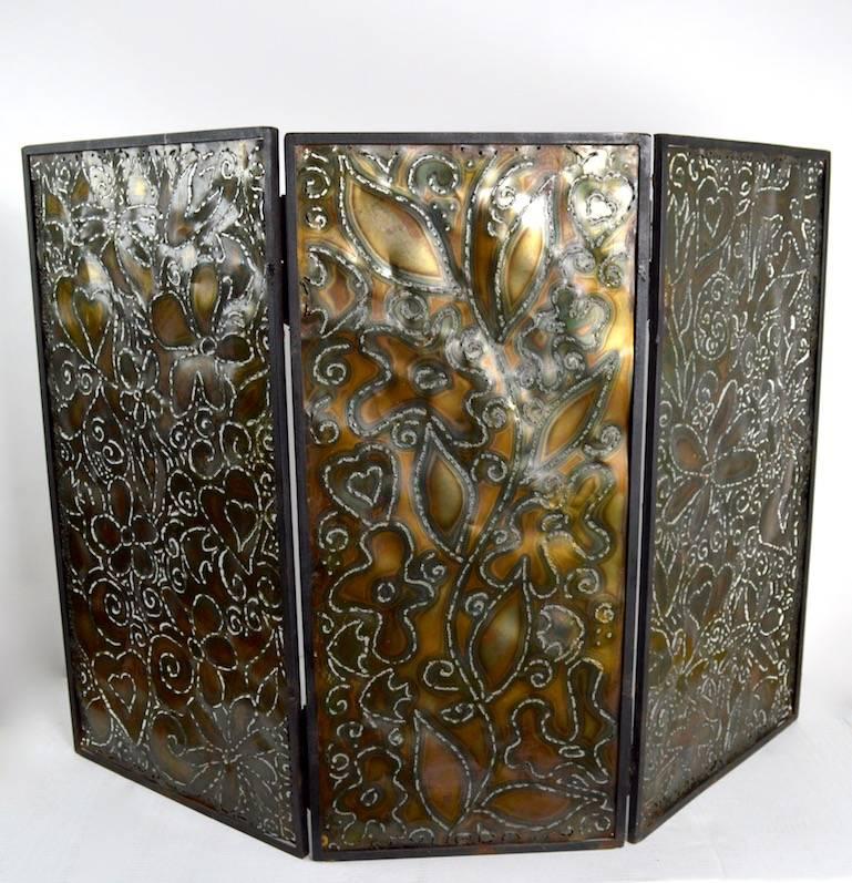 Handmade and unique three fold fireplace spark guard screen. The frame is wrought steel, the interior panels are pierced, and create outlines of flowers, fish etc. Side panels approximately 20 inches W x 36.5 inches H, centre panel 16.75 inches W x