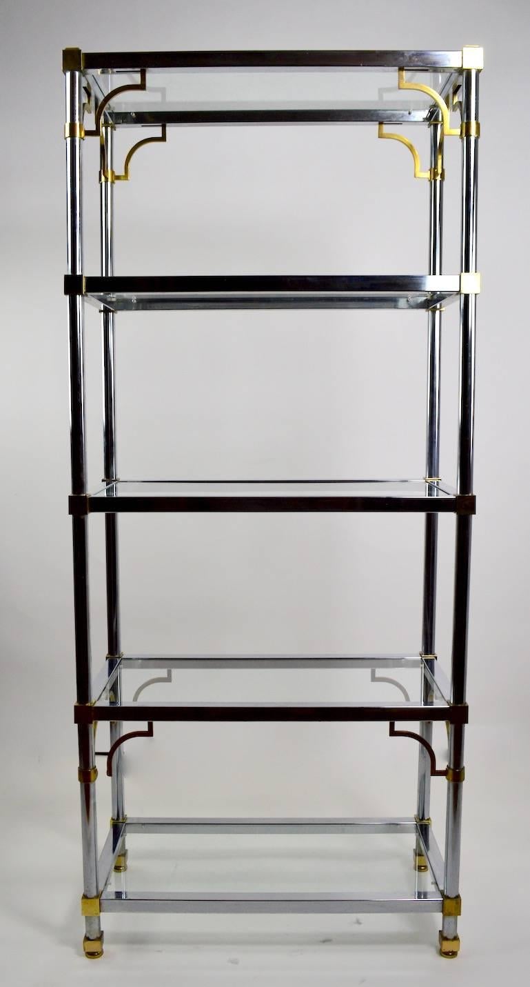 Matched pair of chrome, brass and glass étagères after Maison Jansen. Each shelf unit has five glass shelves
(approximately 15.25 inches between each shelf ). Offered either as a pair, or individually, priced individually.
 