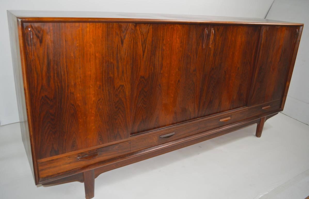 Great quality Danish Credenza, features four doors, which slide open to access adjustable shelved storage, and drawers. 
 Elegant design and expected Danish quality construction and materials, some wear to finish notably darker patch on top surface,