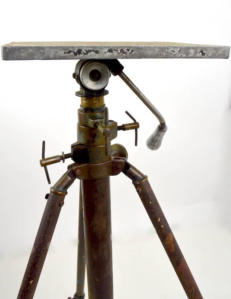 Very nice Industrial tripod base adjustable stand. Probably originally functioned as a camera, or transit stand, this can function well as a sculpture, or display stand. Height in tallest position 77 inches, top surface 9 x 7.
   