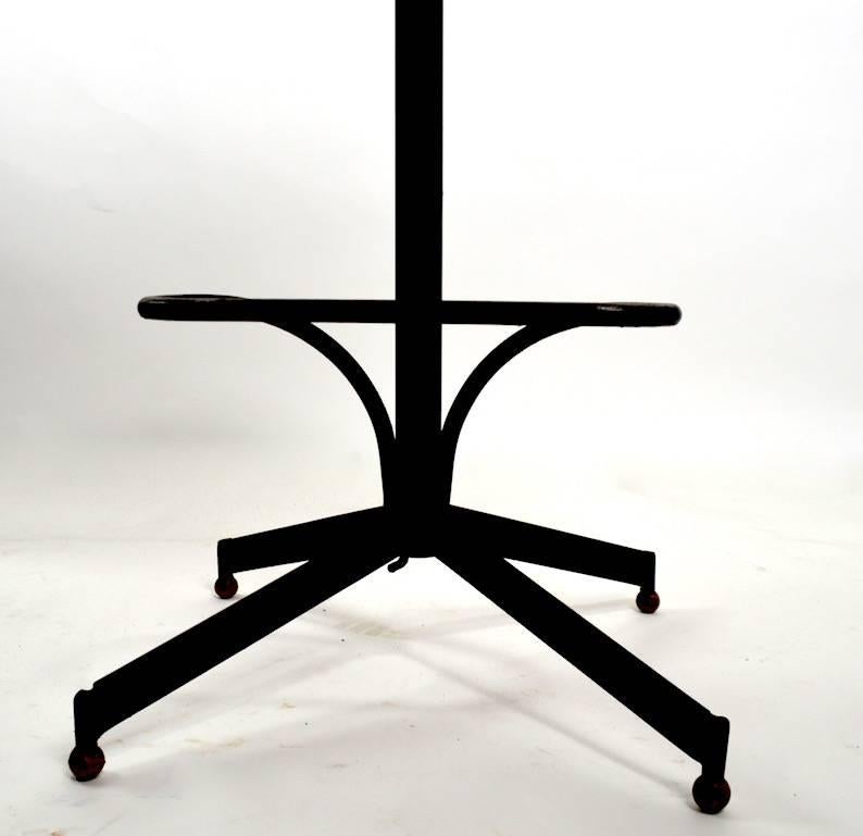 Four orange fiberglass bar, counter stools on stylized iron base. These stools swivel, and feature a wrought iron footrest, as shown. Design and manufactured by Burke, with obvious Eames influence. Original, clean, ready to use condition.
Footrest