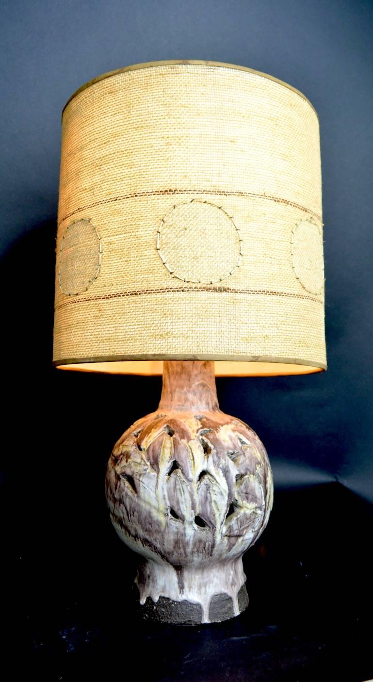 Interesting pottery lamp with reticulated stoneware base and muted earth tone glaze. Original hand sewn burlap shade included (shows some cosmetic wear). Recently professionally rewired, and working, accepts standard screw in bulb.