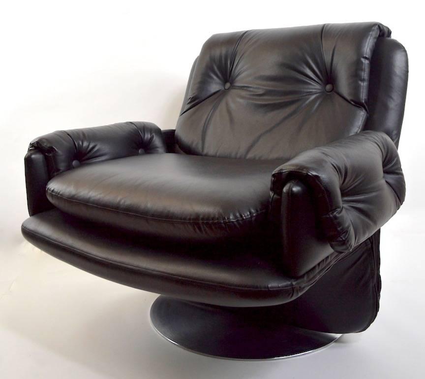 Pair of large Modernist school black leather swivel lounge chairs, each mounted on solid brushed steel disk base (23 inch diameter). Great quality, probably Italian made, however unsigned. Selling and priced individually, however we'd love to see