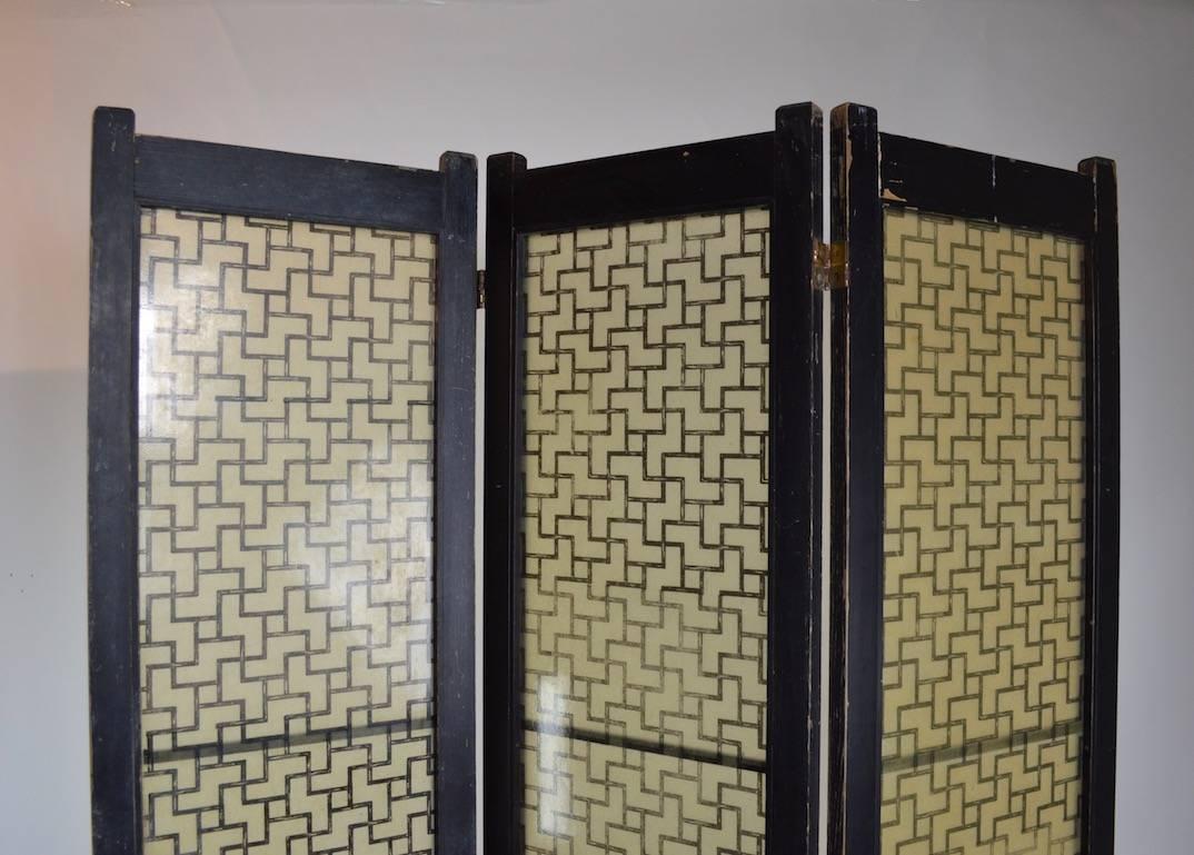 Interesting and graphic three panel folding screen by Tropicraft of San Francisco. The outer frame is painted black wood, the inner decorative panels are  translucent sheet plastic with a "Chinese" grid pattern motif. The screen shows some