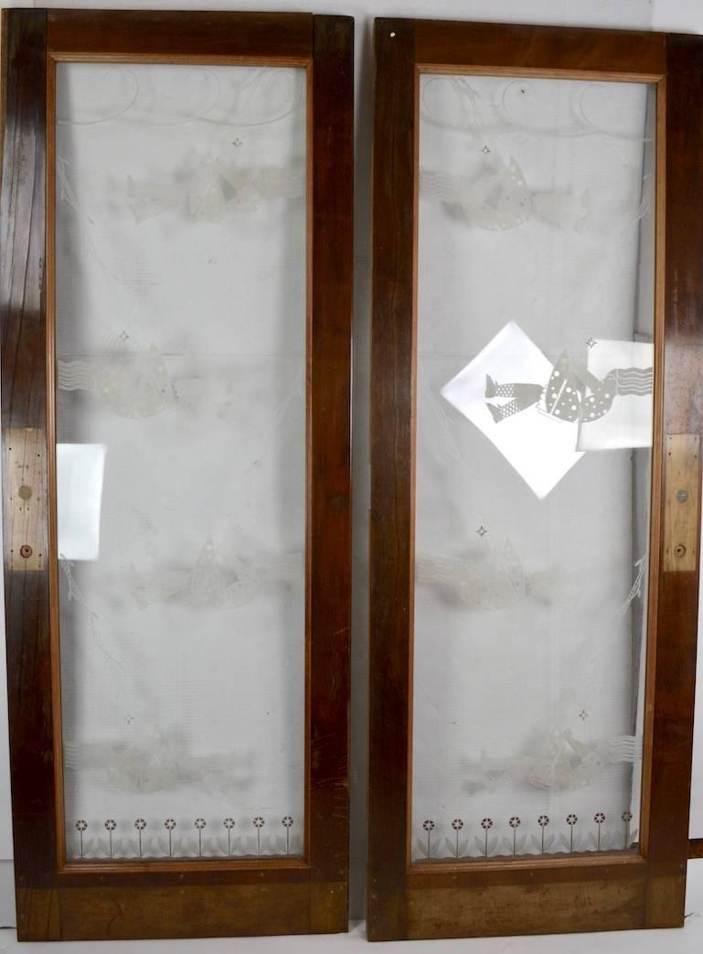Pair of Art Deco doors, each having a deeply etched centre panel depicting stylized young girls on a swing. The centre panels are mounted in heavy wood frames, wood framed show some minor wear, and are missing the hardware. Wonderful quality,