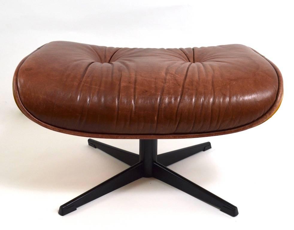 Leather chair and ottoman in the style of Eames, attributed to Selig. The headrest shows a stain from use by the original owner, as shown. Ottoman dimensions 26.5 W x 22 D x 16 H. Chair 33.5 W x 35 Total H x 16 Seat H x 33.5 Depth. x 21 Arm H. Chair