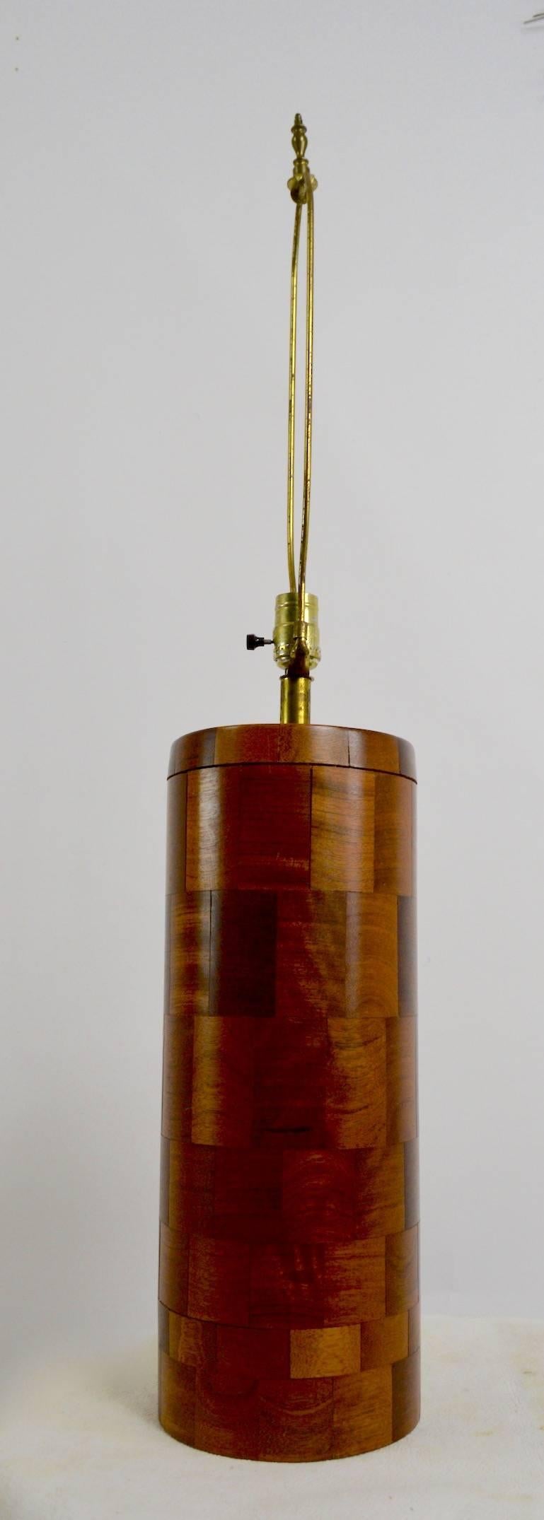 Cylindrical wood lamp of stacked wood construction, in the style of Phillip Powell. This lamp is in good original, working condition, the shade shown is not included. Height to top of wood body 18 inches. Nice example of craft in the Modernist idiom.