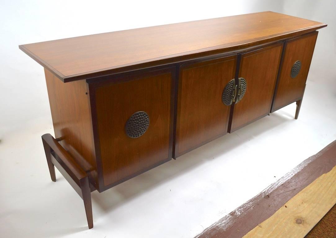 Stylish midcentury credenza, dresser by Helen Hobey for Baker. Very well constructed with complex angular forms and asymmetrical dimensions. This dresser features four doors, all open to revel interior drawers providing ample storage.
This example