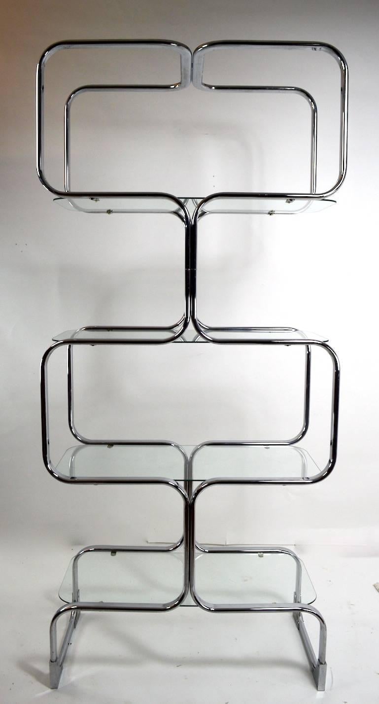 Stylish pair of chrome etageres designed by Milo Baughman, each having four oval plate glass shelves. Individual shelf heights as follows 12, 28, 45, 62 inches. Chrome plating is bright and clean, glass shelves are free of damage. Offered and priced