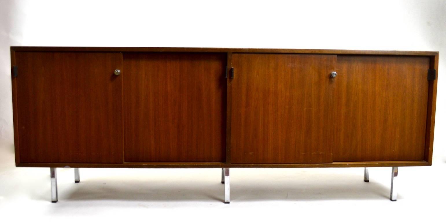 Classic Florence Knoll credenza, walnut with leather handles, chrome lock knobs (key not included) and Formica top. Four storage cabinets, two with shelves. This example is in good original condition, however does show some cosmetic wear and