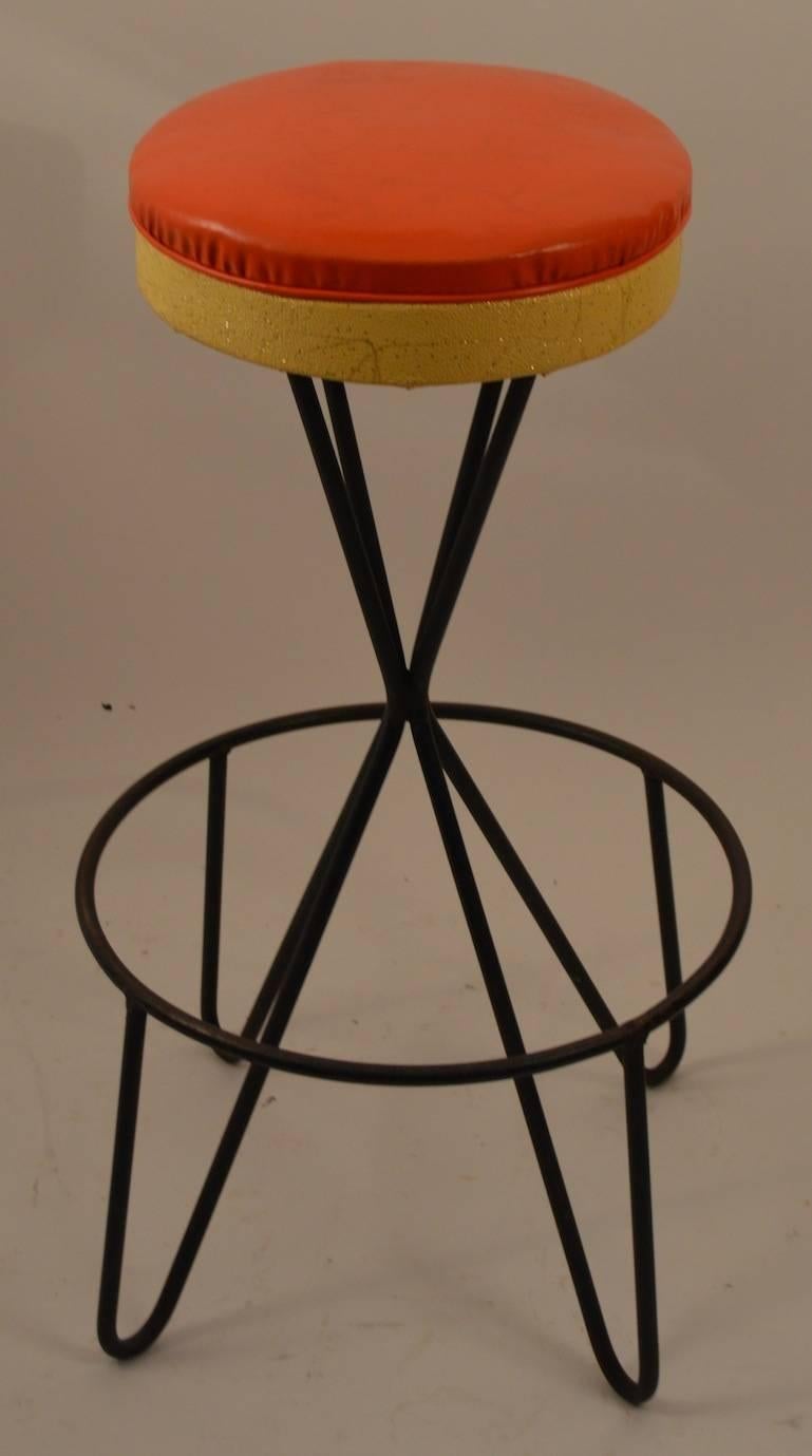 Nice set of four swivel bar, counter height stools designed by Paul Tuttle. Original orange and yellow vinyl upholstered seats, wrought iron base. Very fine original condition, extra small blemish on one seat, all in ready to use condition.