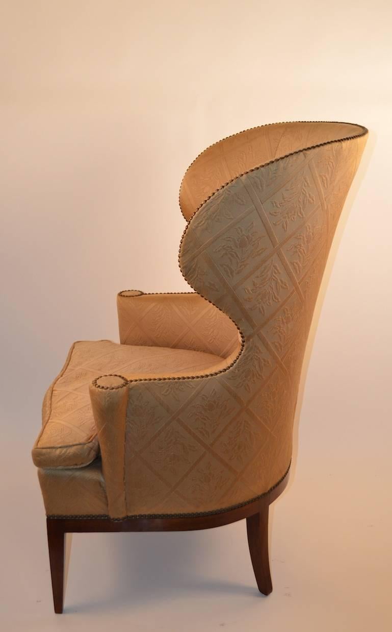 Wrap around barrel back wing chair with studded upholstery. The fabric shows some wear and staining.