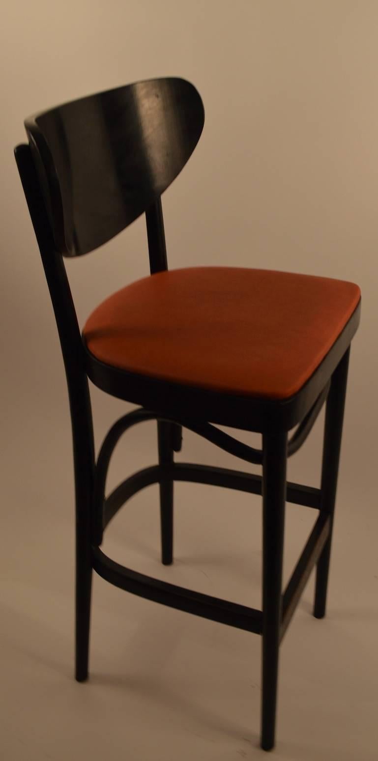 Five counter, bar stools having a curved backrest, upholstered seat, and footrest rail. original black finish with original dark orange seats.