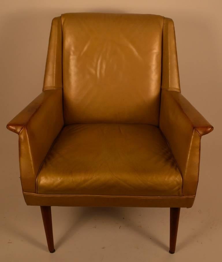 Mid Century leather lounge chair, in gold finish, on tapered pole legs. This stylish chair shows both Danish, and Italian influences. It is in good original condition, showing expected wear, and patina normal and consistent with age.