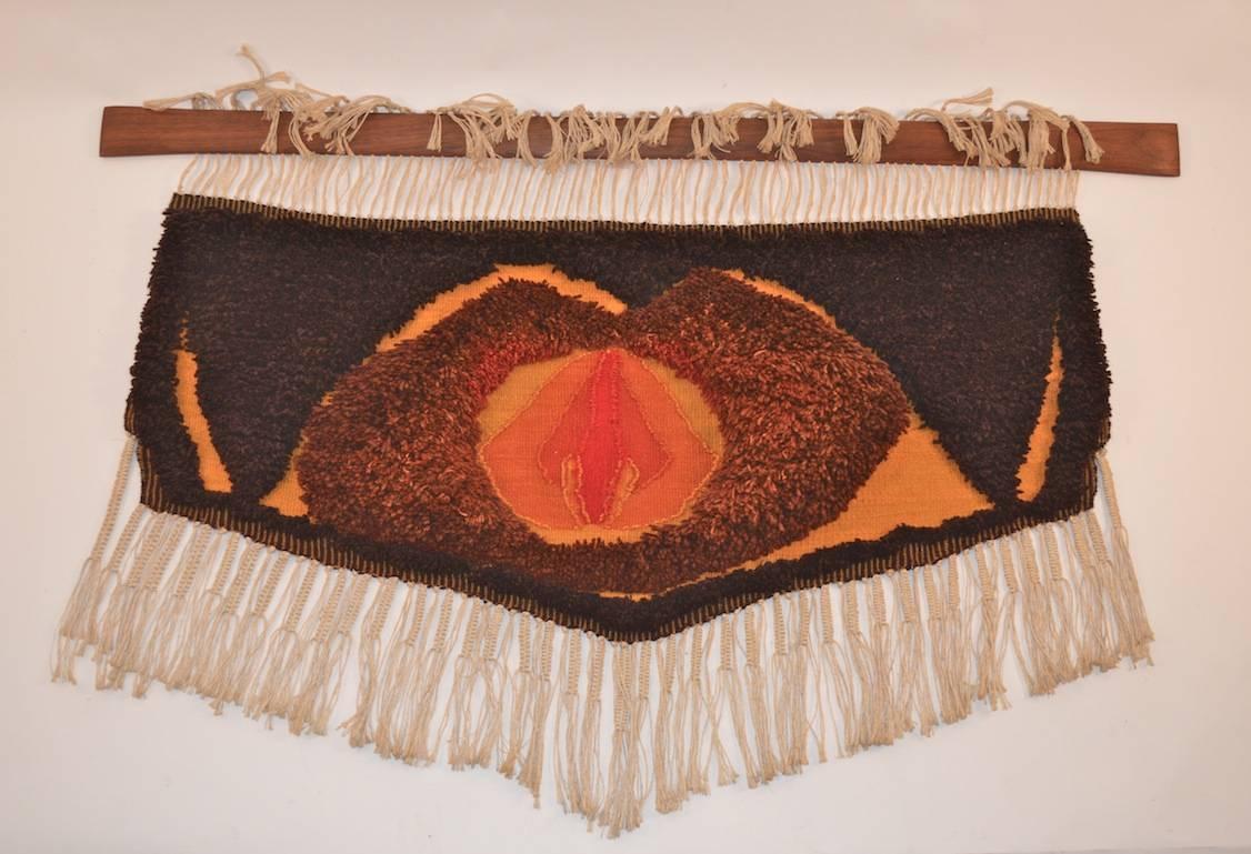 Well done Macrame Art Wall Hanging by Rigina  Medely  of Virginia Commonwealth University.  Circa 1970. The thick pile wool sculpture  hangs from a tapered wood bar, which hangs from the wall. Vintage abstract textile work by a working Artist