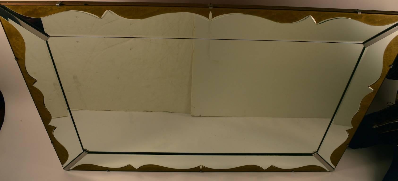 Miroir Art Déco inhabituel, avec un cadre en miroir et une garniture décorative dorée. Actuellement configuré pour être suspendu horizontalement, mais il peut être facilement reconfiguré pour être suspendu verticalement. Grand miroir en verre plat,