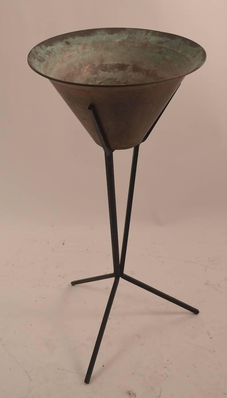 Brass insert planter rests in tri part blackened iron stand. The planter shows tarnishing and surface wear, normal and consistent with use. 