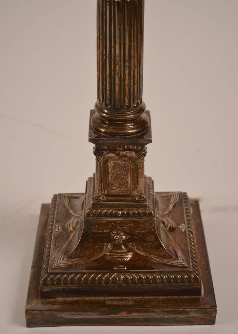 Paire de lampes à colonne classiques en métal argenté, à décor d'urne et de houppe sur la base. Fonctionnement, état d'origine, abat-jour et fleurons non inclus. Hauteur au sommet de la colonne 22