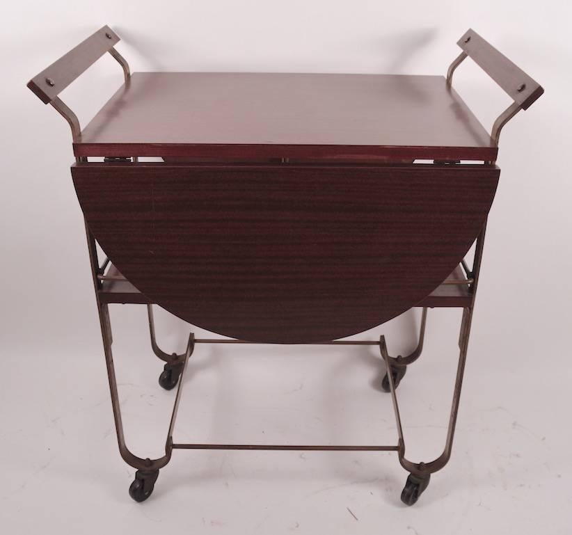 Interesting version of the Classic Treitel Gratz bar or serving cart form. This example has a wood top, with formica veneer, which when open creates a large (41