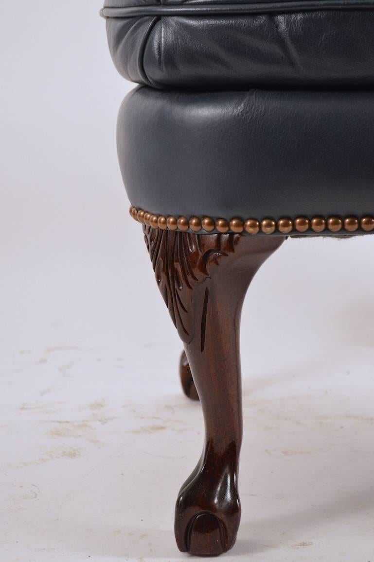 Tufted leather ottoman with brass tack trim and carved cabriole, ball and claw foot legs. Manufactured by the 
