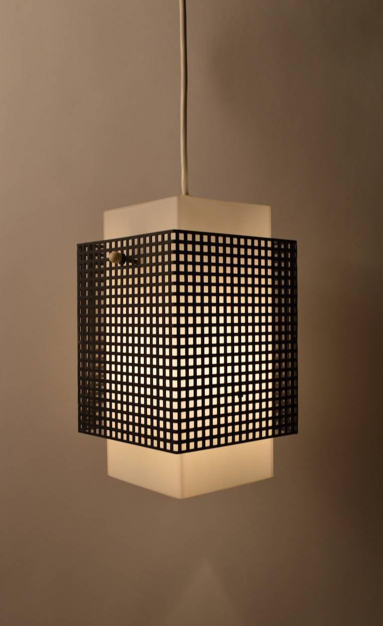 Perforated black metal shade surrounds white glass diffuser, suspended from white cord, original white plastic ceiling canopy included. Sophisticated European Minimalist design reminiscent of Sarfatti or perhaps Wirkkala. Outer metal shade 6.75