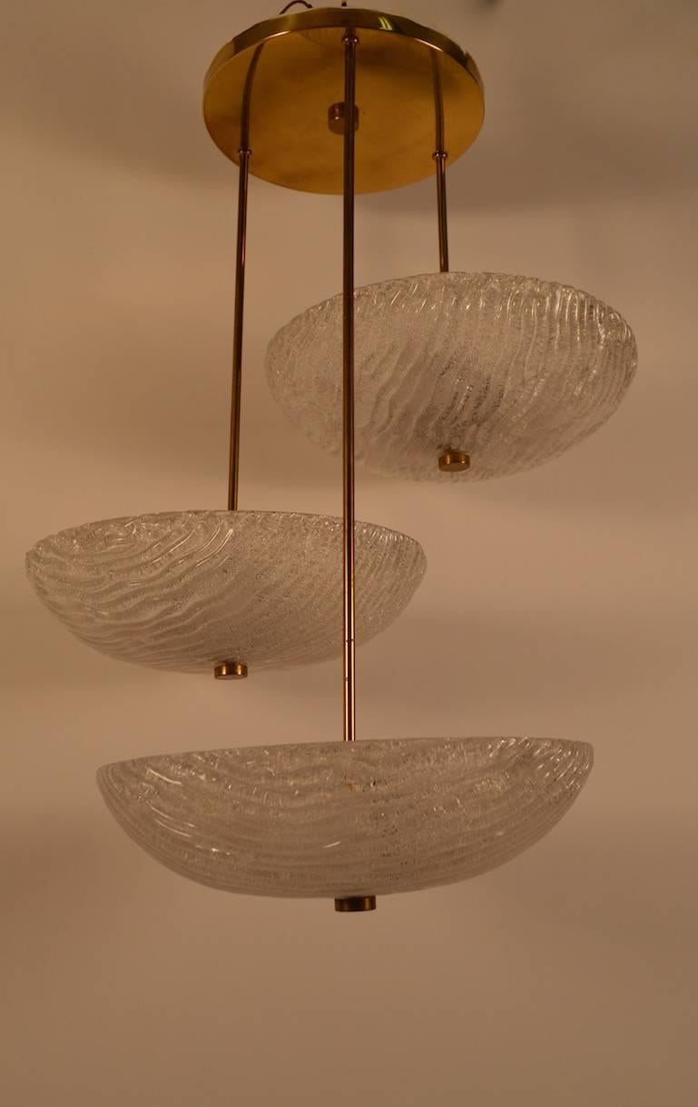 Three textured glass bowls suspended from brass tubes, create a large and impressive chandelier. Each bowl shade 15
