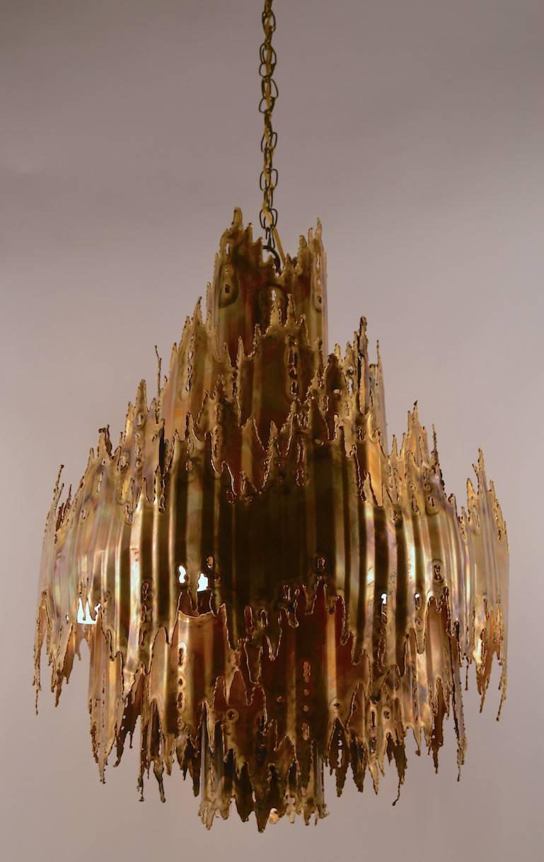 Seven-tier torch cut chandelier by Tom Greene for Feldman Lighting Company. This hanging fixture has six bulbs circling the center and one down light socket, it is in excellent working, ready to install condition. Dimensions in listing do not