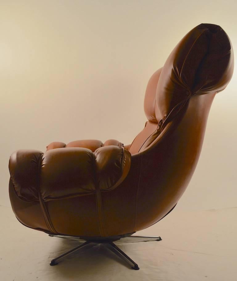 Classic American, 1970s overstuffed swivel tilt lounge chair, on bright chrome star base. Tan vinyl upholstery on egg shape frame.