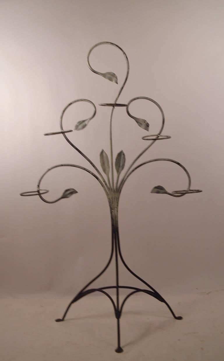 Wrought iron freestanding plant stand by Salterini. This example hold five pots, standing on tri part base, suitable for indoor or outdoor use.