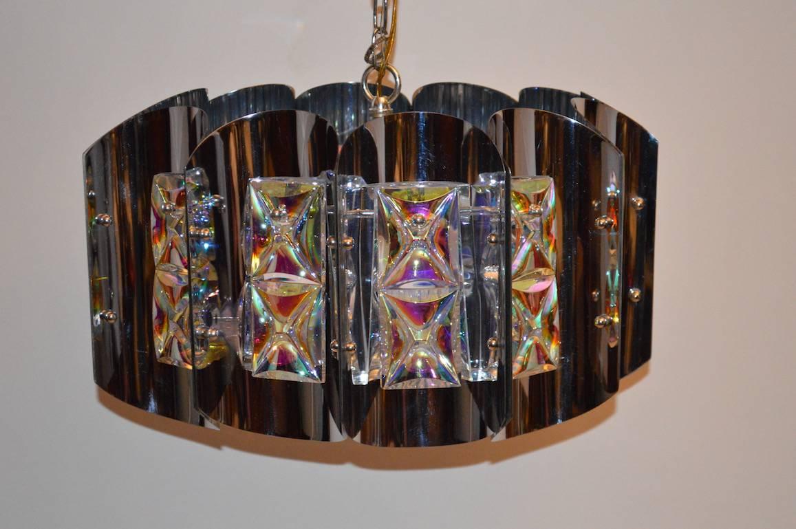 Twelve curved chrome panels each having two faceted iridized glass panels form a circular hanging fixture. This chandelier comes with the original chain and canopy, is in extra fine, original condition, and marked 