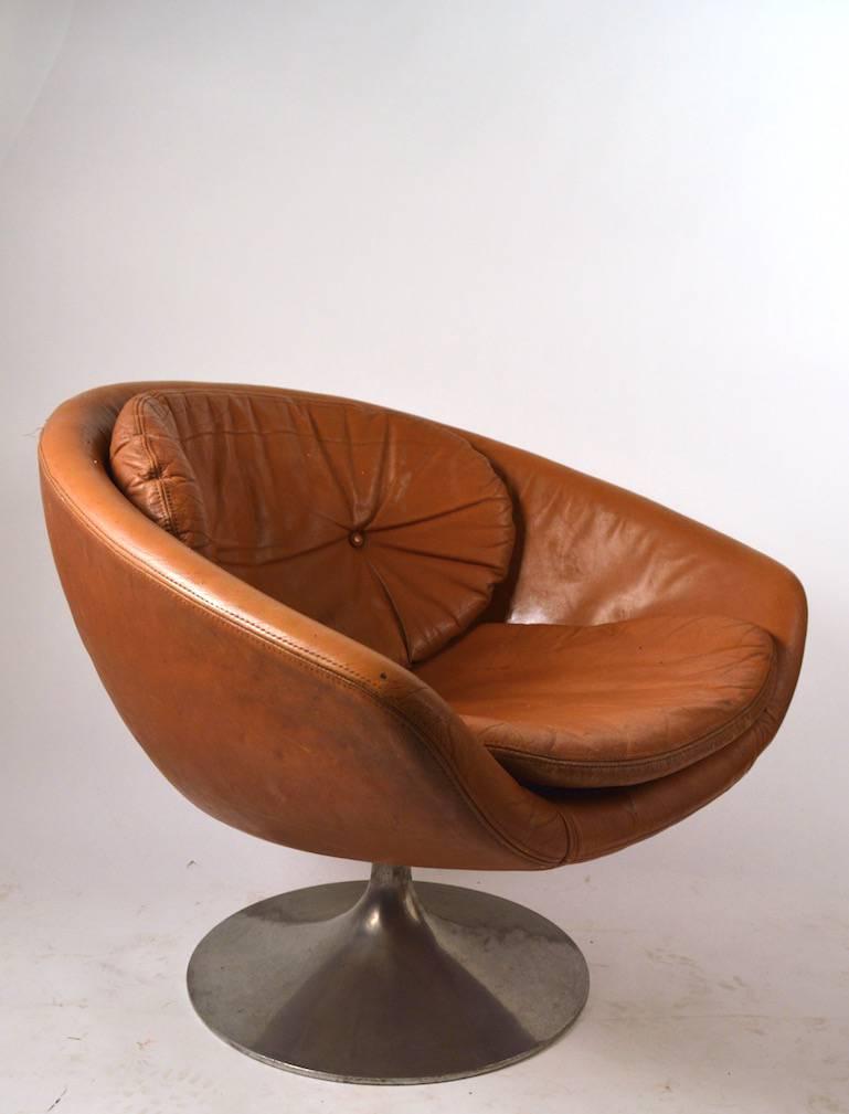 Swivel pod chair with cast aluminum base, by Overman of Sweden, unusual to see this chair in leather upholstery. The leather shows wear, and the back cushion is missing one button as shown. Usable as is if you like the distressed leather look, or