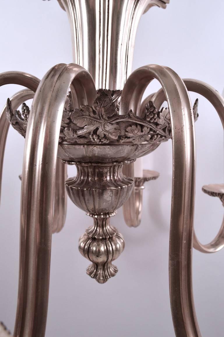 Eight candle style arms radiate out from the foliate decorated body. Clean, recently rewired ready to hang condition. Height of chandelier without chain 22