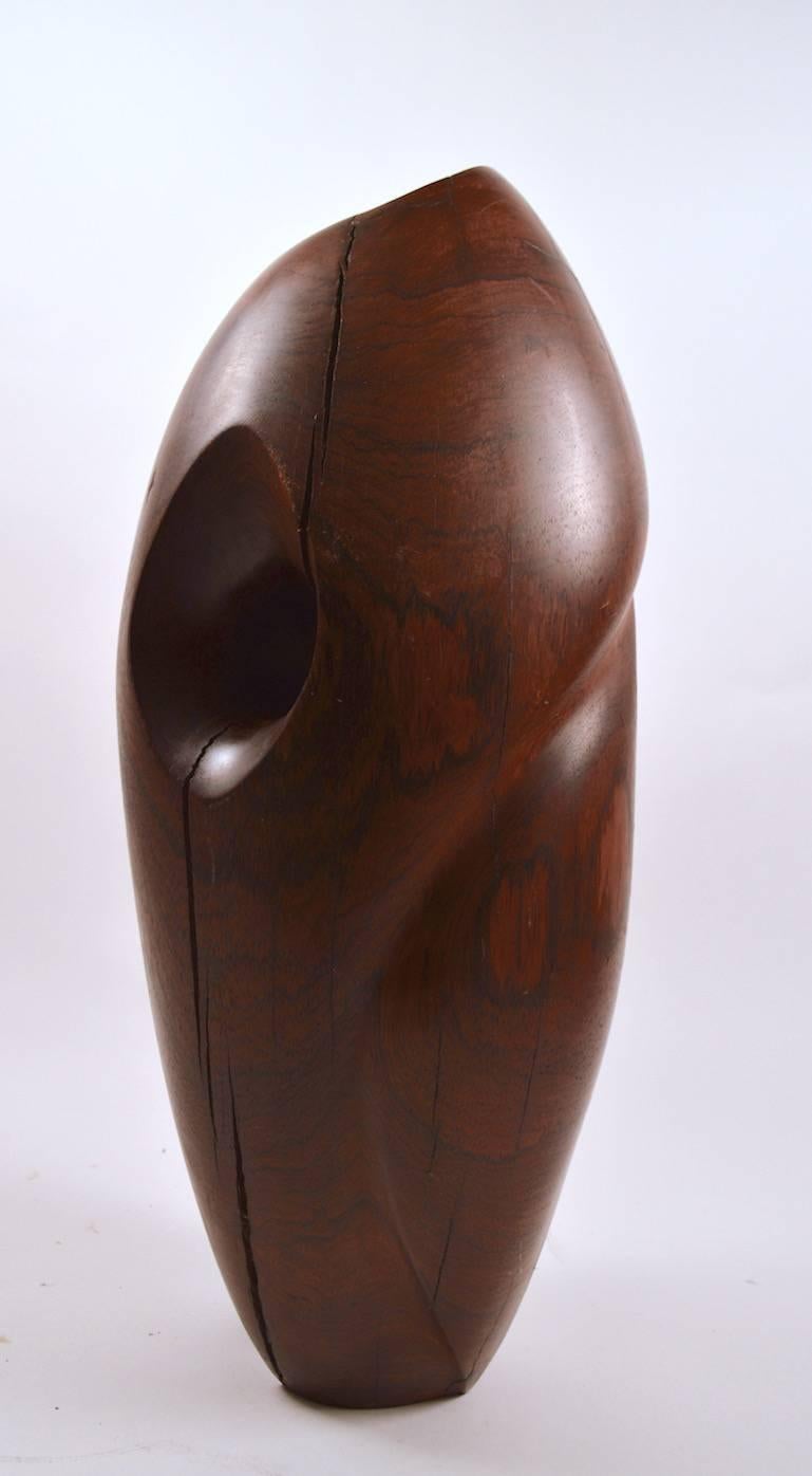 Impressive solid rosewood sculpture, organic form, with rich original patina.
The freestanding oblong shape flows visually, with a sinuous top to bottom curve, and a hole that adds to the flow and life of the piece.
Over the years, the wood has