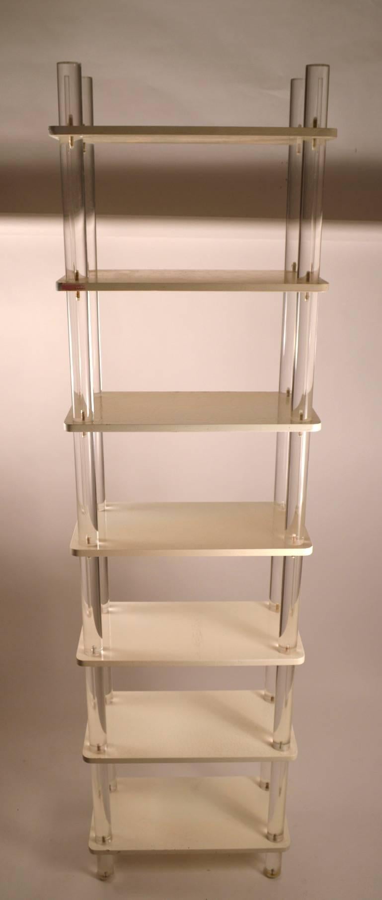 Thick cylindrical vertical elements support white painted wood shelves. Seven shelves approximately 12
