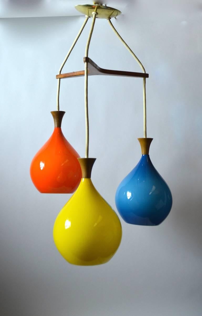 Three teardrop form glass shades of Orange, Yellow and Blue, hang in staggered descending form. Clean, original, working condition, each globe 10