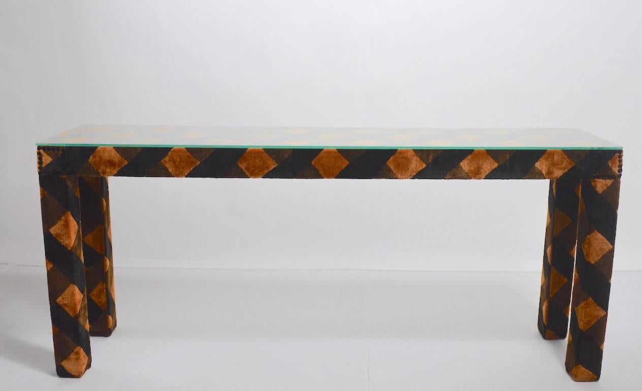 Upholstered Parsons style console table with original plate glass top. This table has three colors (black, tan, brown) which are 