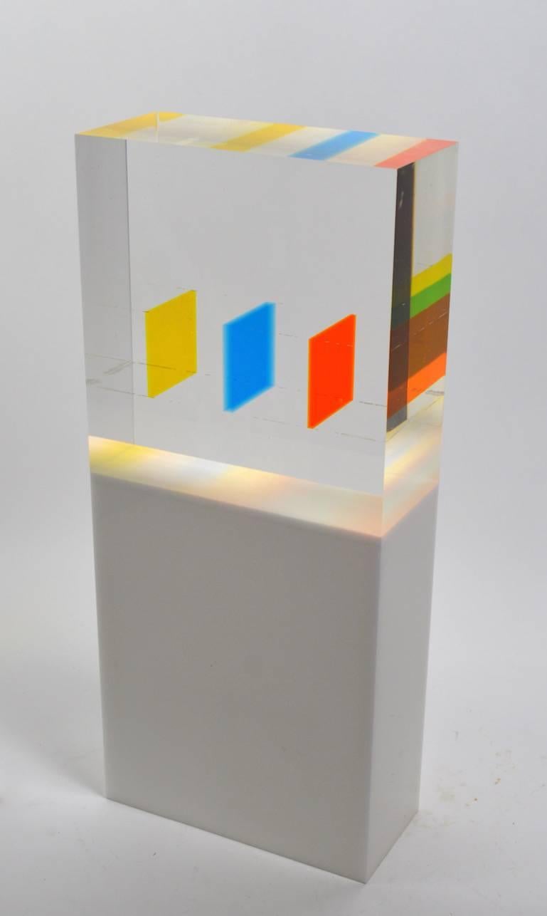 Classic Dennis Byng Lucite cube sculpture signed Byng and dated 1-11-69. The multi colored elements create an interesting prismatic effect as one views the object from various perspectives, clear block top on solid white Lucite base.
