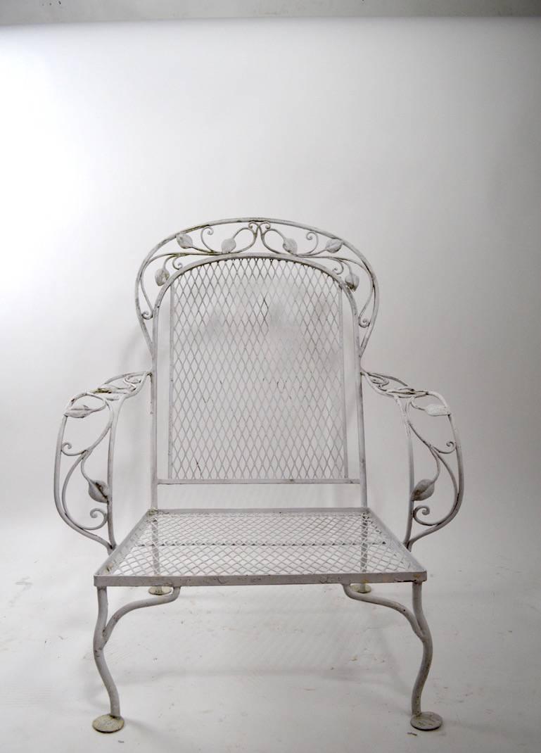 Pair of wrought iron lounge chairs of dramatic form. Striped cushions show wear and are probably not original, metal frames are free of damage. Please view the matching sofa we have listed if you have an interest in more pieces.