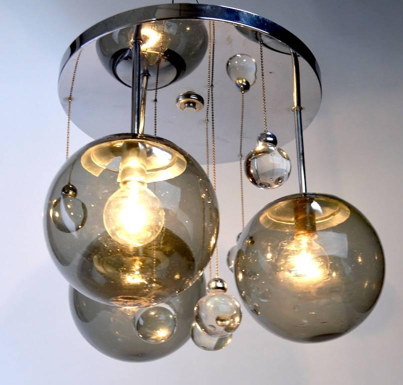 Stylish chrome and glass ball drop chandelier. The circular chrome disk mounts to the ceiling crystal balls hang from chains as decoration, with three smoked glass ball globes which illuminate. 
 Pure chic style, clean, original and working