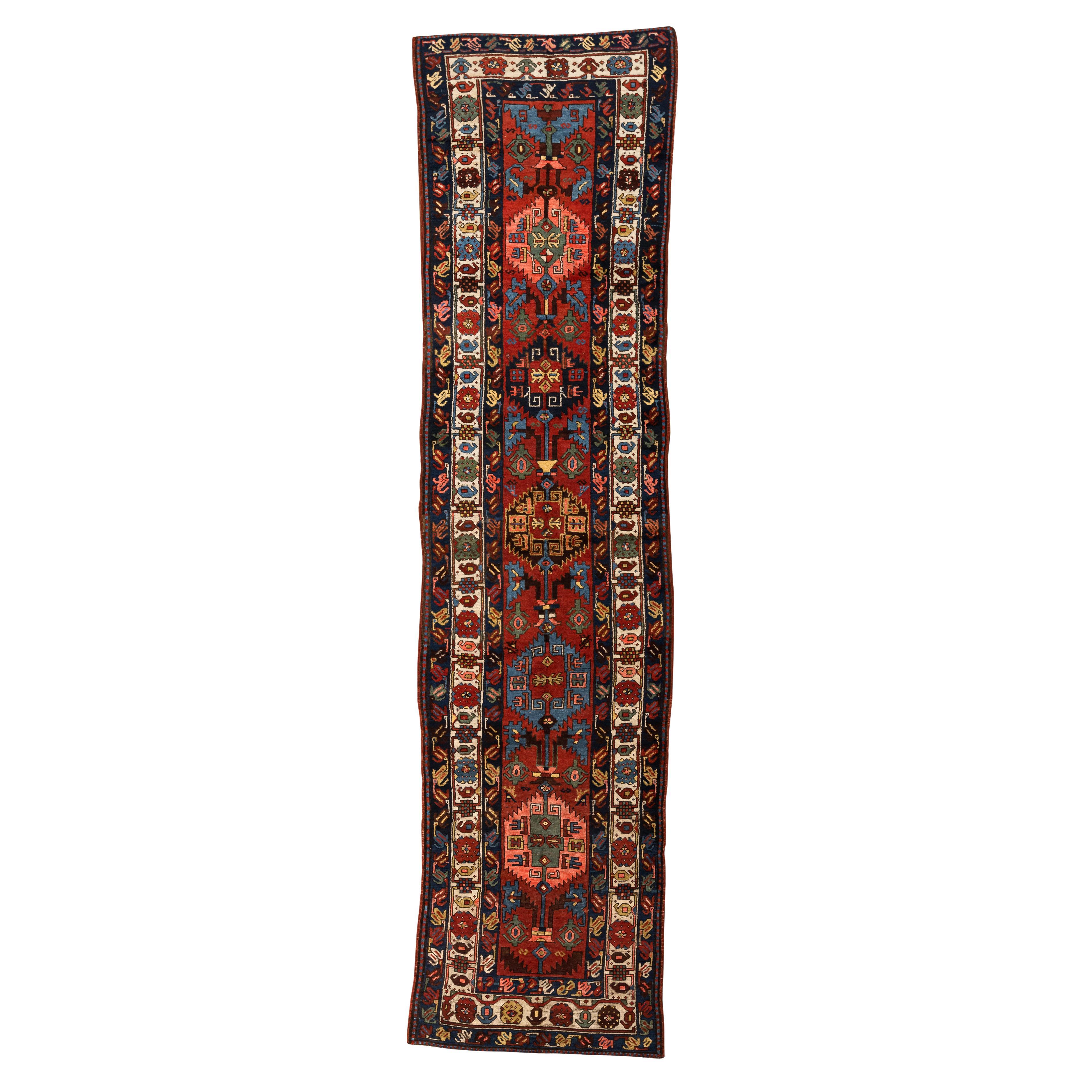 Antiker Kazak-Läufer - Lebendige Farben und kräftiges Design

Dieser antike Kazak-Läufer mit seinen fünf gezackten Medaillons, die durch zarte florale Äste verbunden sind, bringt Farbe und geometrische Kunstfertigkeit in Ihr Zuhause. Das kräftige