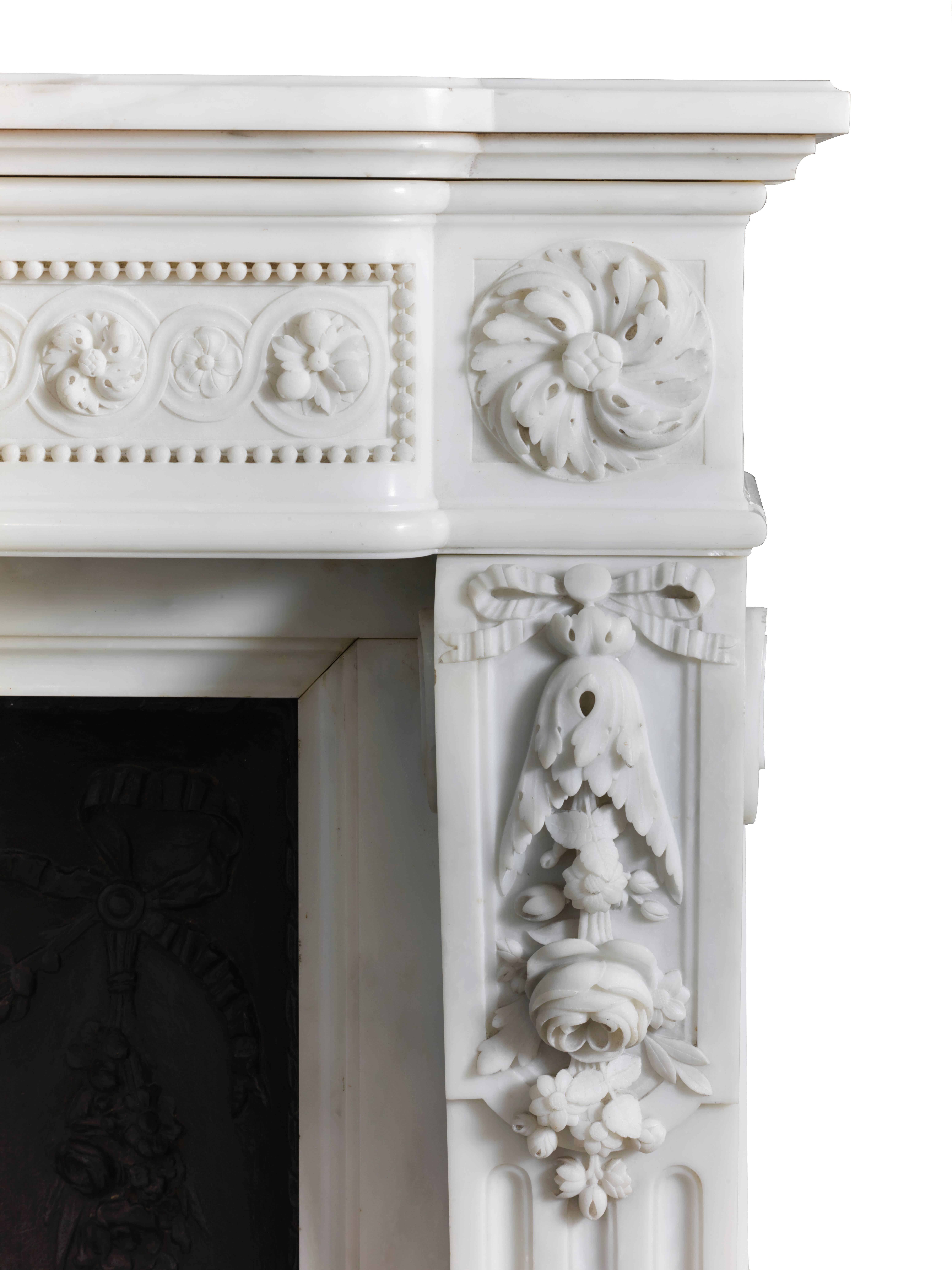 An impressive white marble Louis XVI mantel of inverted breakfront design with a beaded floral guilloche frieze and tied ribbon floral swag centre tablet, supported by tied ribbon floral console jambs with honeysuckle flutes surmounted by concentric