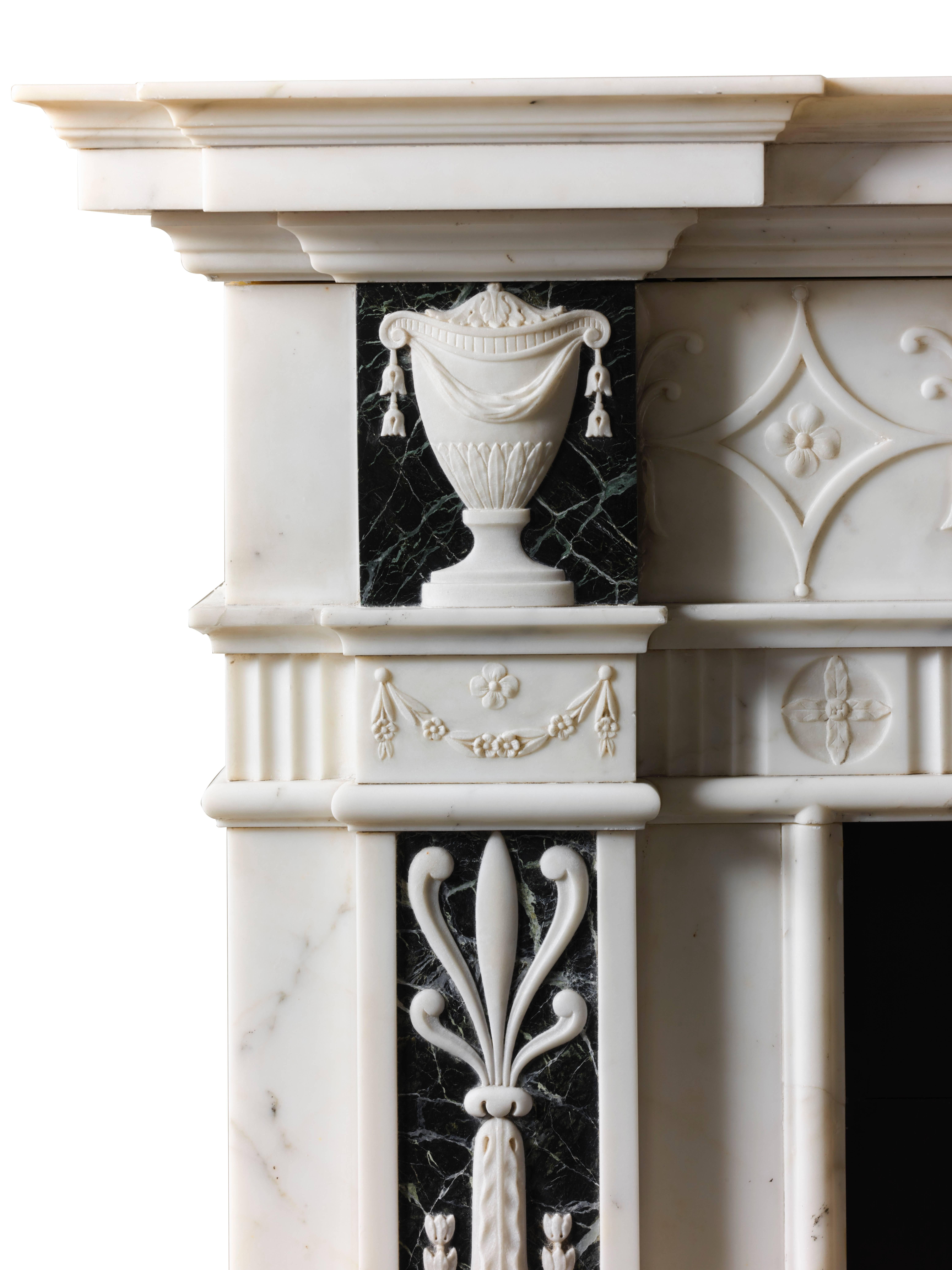 A very unusual statuary marble antique chimneypiece carved in the Adam style with Verdi Antico accent panels with very finely carved statuary applied decoration. The delicately carved frieze flanks a lidded tazza center tablet and draped lidded urns