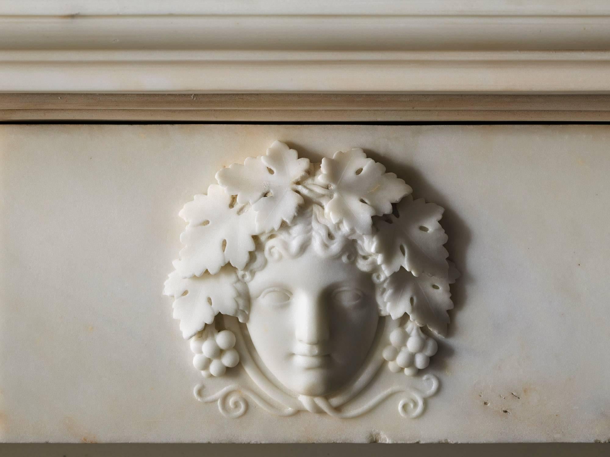 An exceptional English Regency antique chimneypiece, circa 1820. Carved in fine, white statuary marble with full fluted columns with Corinthian capitals. The frieze is carved with ovoid floral bosses on either side of a beautifully carved center