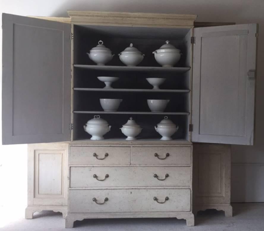 A rare two-part English breakfront housekeeper's cupboard hand-scrapped to the original paint on the exterior with later paint on the interior. This charming cabinet has retained all of its original keys.