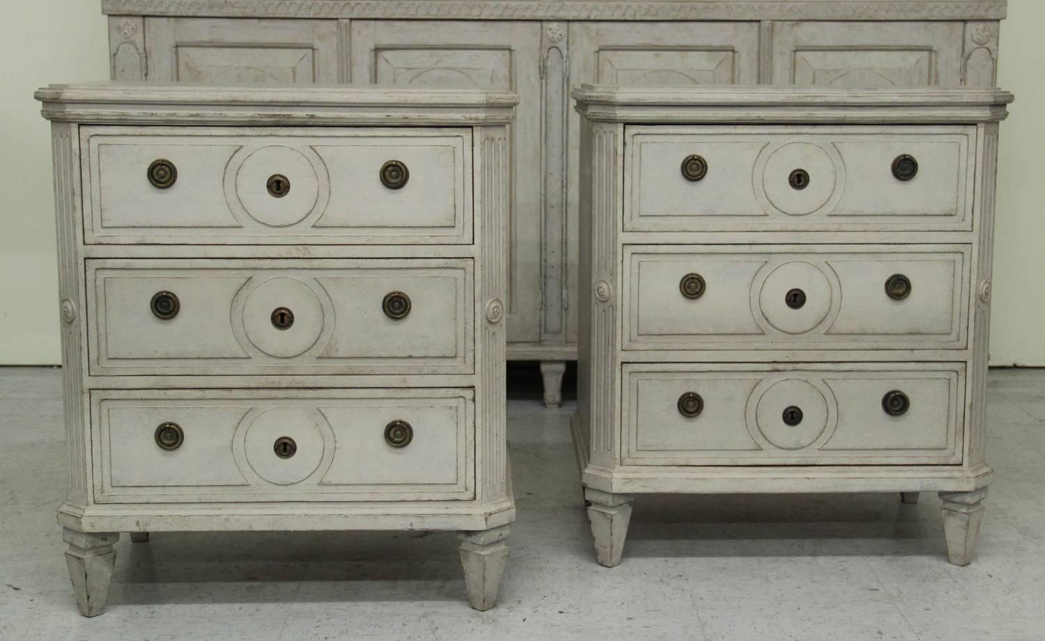 A beautiful pair of Swedish painted chests in the Gustavian style with canted and fluted corner posts and square tapered legs. Each chest has three drawers and brass hardware.